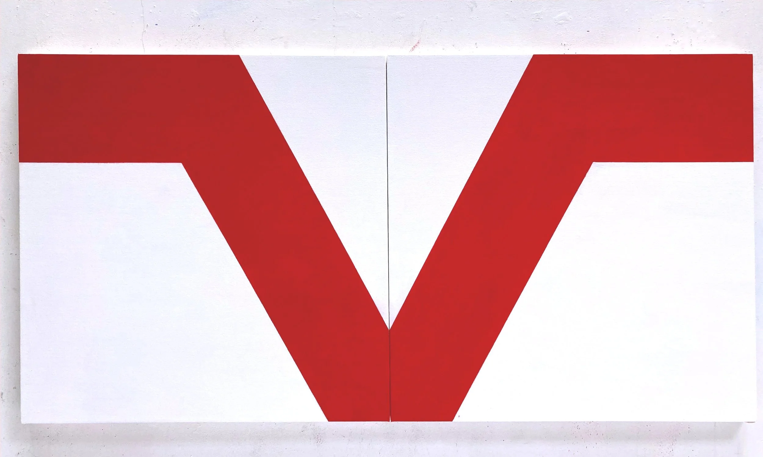 A white wall with a large white cardboard with red pattern in the center.