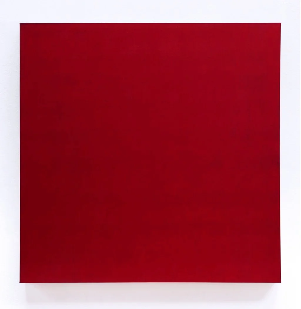 Red square artwork mounted on a white wall.
