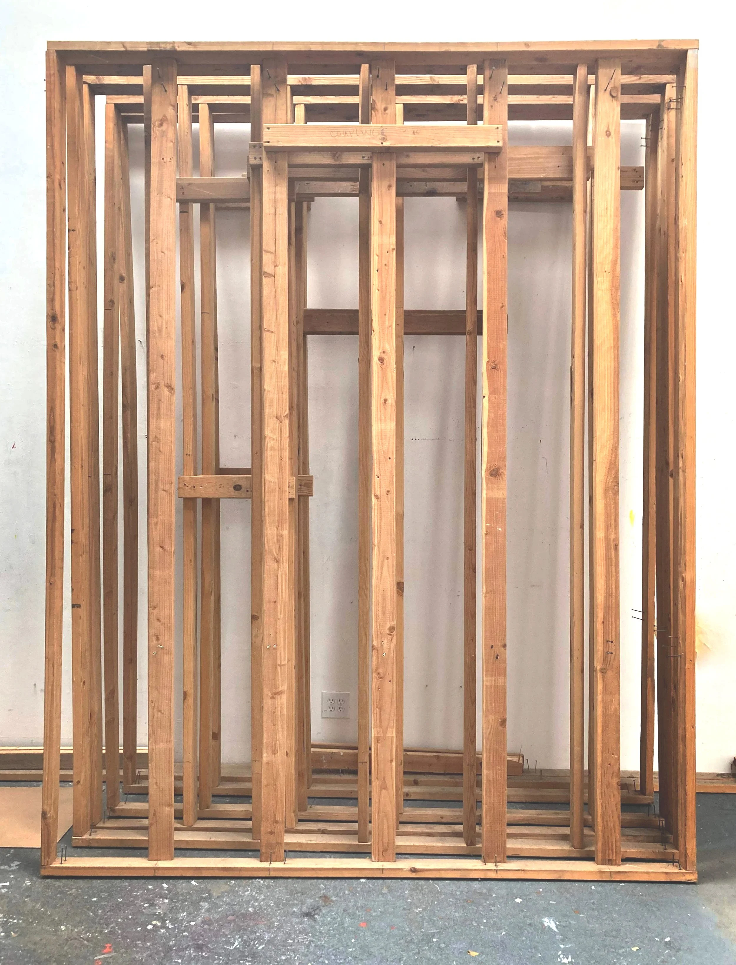 Bare wooden framing for a wall or structure in a workshop or construction site.