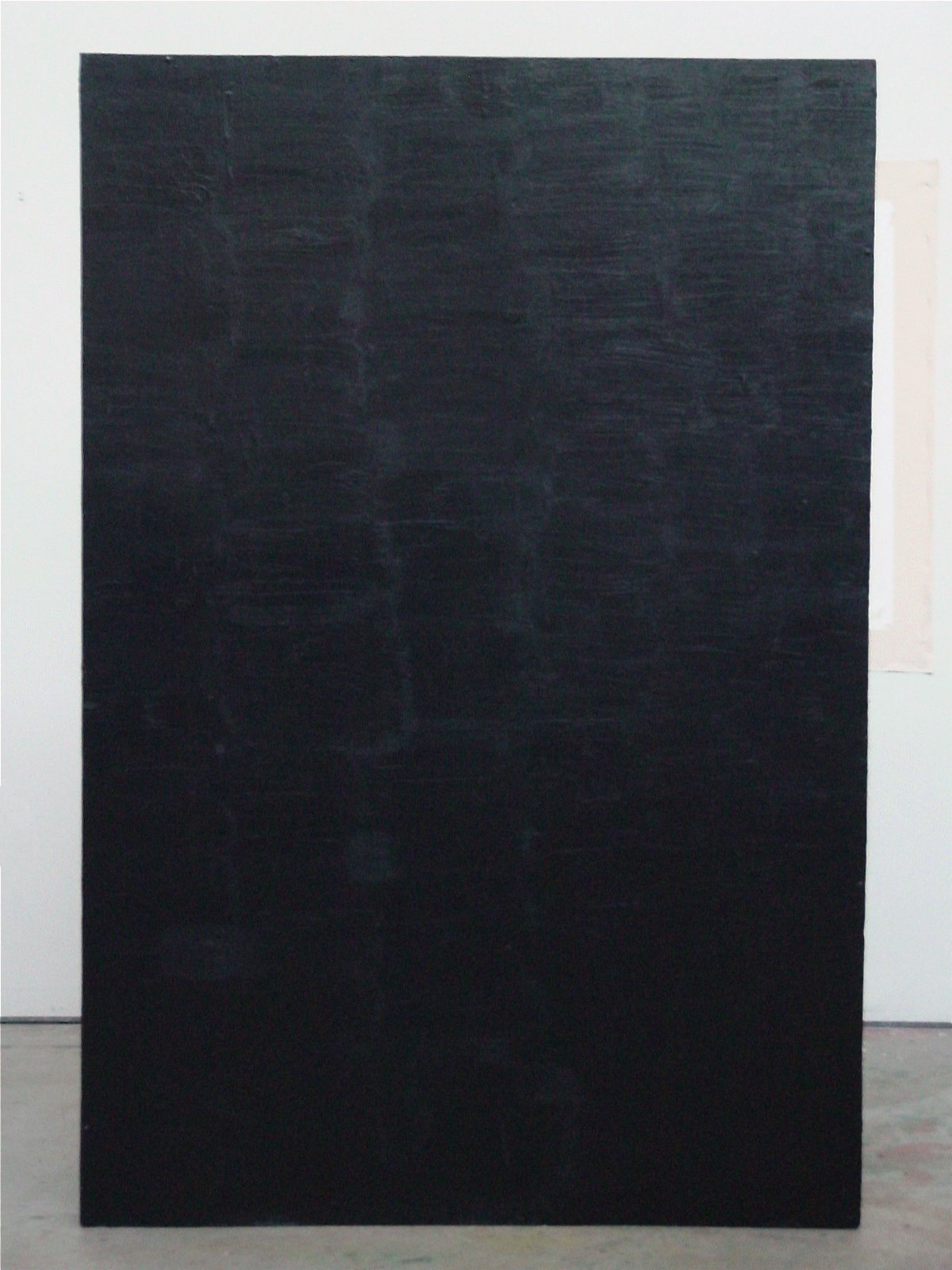A large black rectangular chalkboard standing against a white wall in an indoor space.