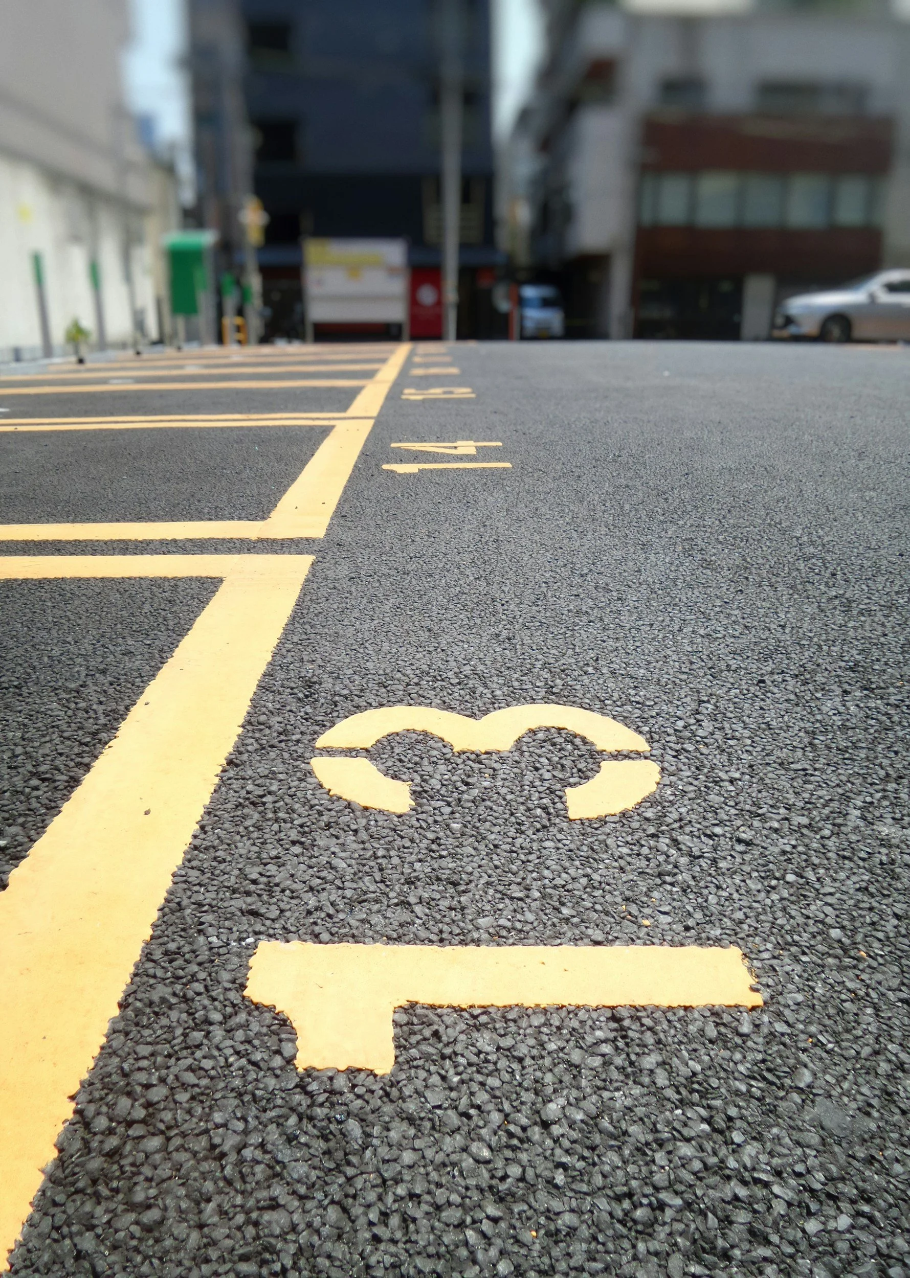 Close-up of a parking lot space marked with yellow paint, numbered 22, on dark asphalt with textured surface.