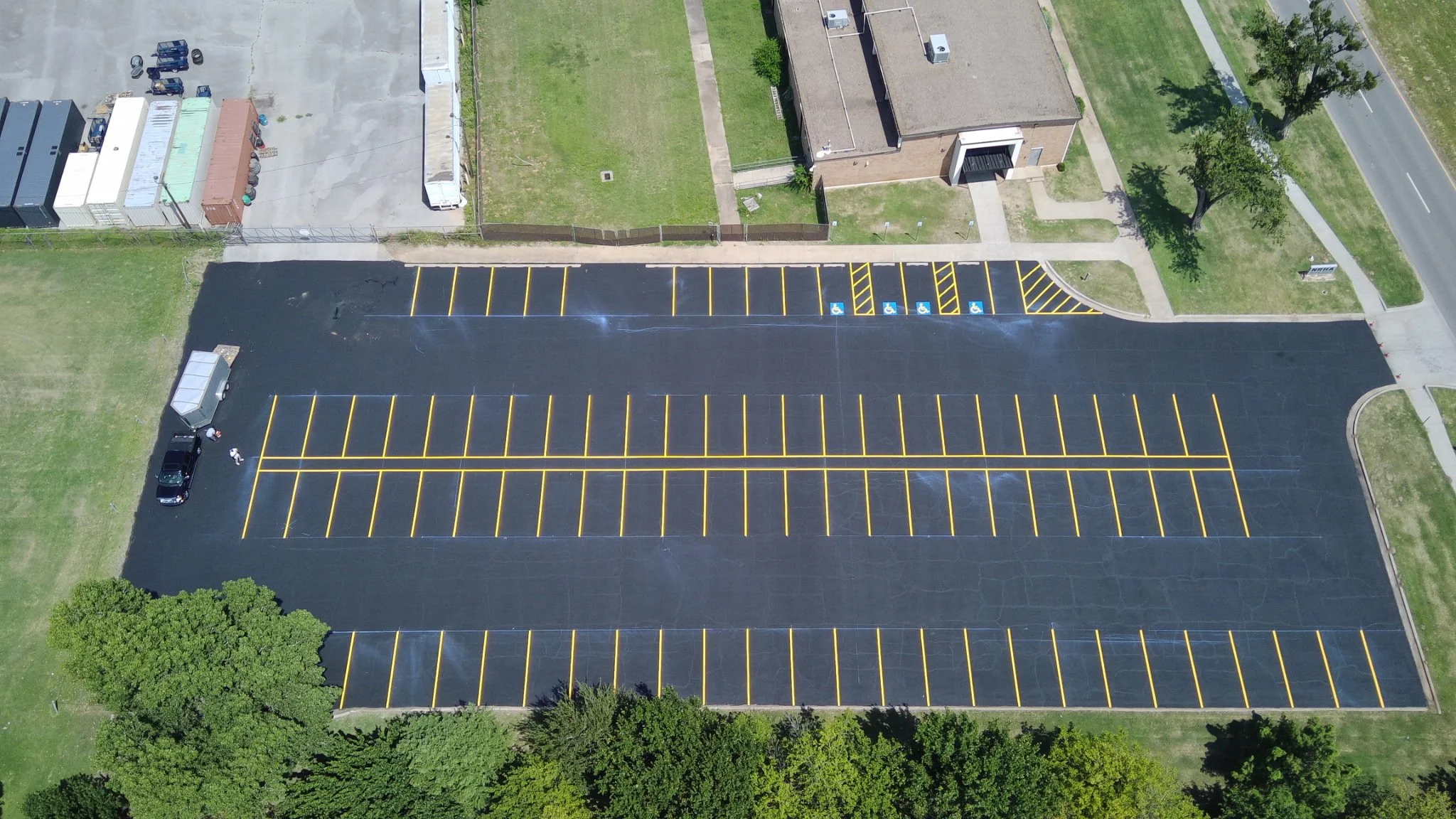 After: aerial view of a parking lot freshly sealcoated and restriped, with ADA accessible spaces