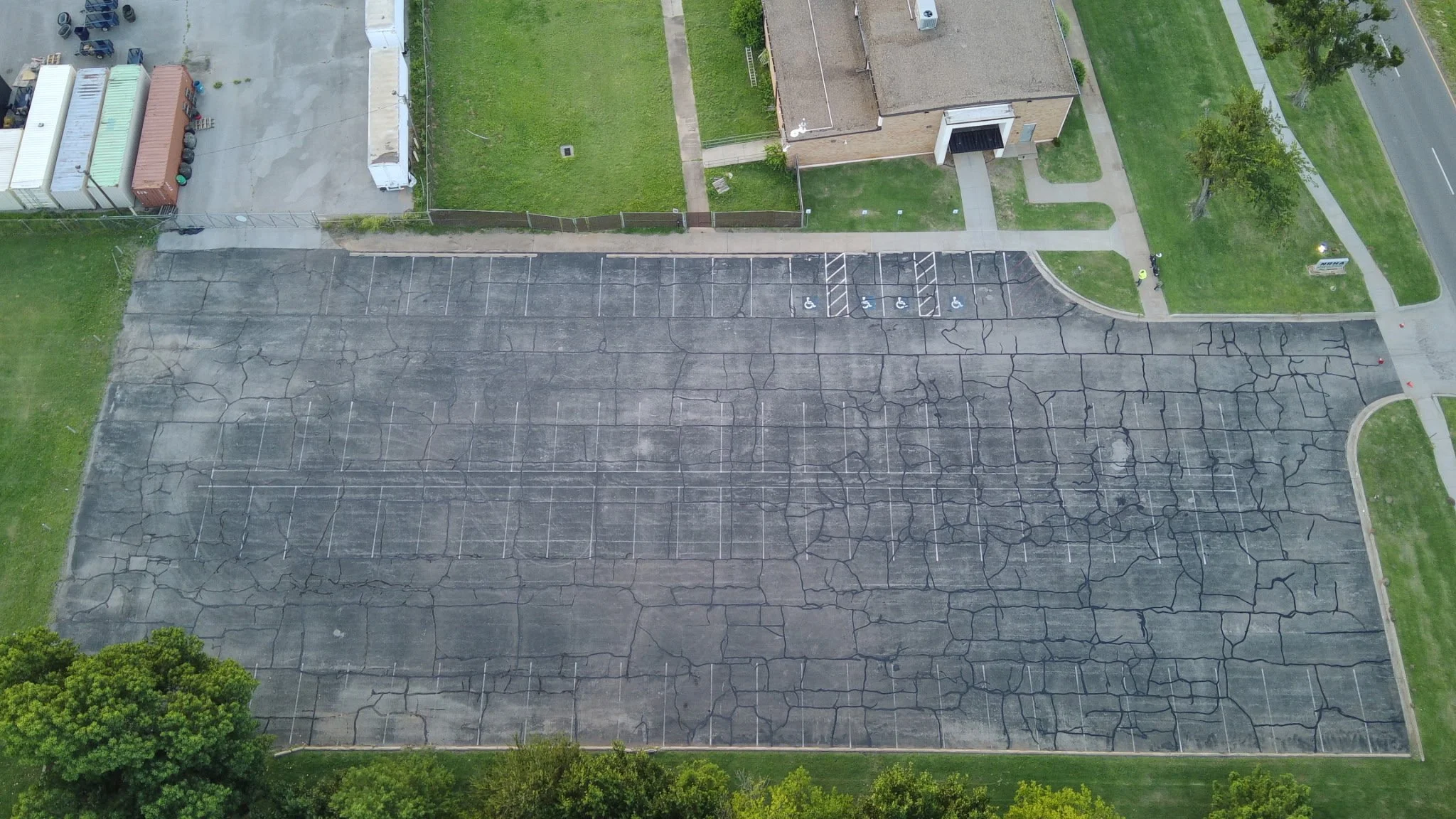Before: aerial view of a faded, cracked parking lot prior to sealcoating and striping