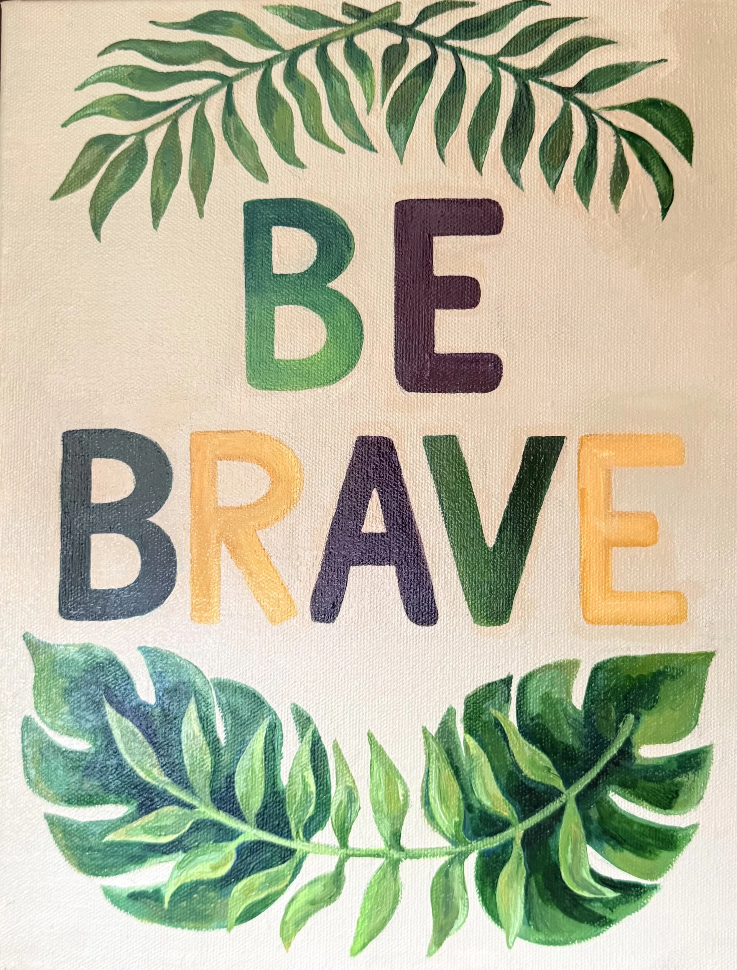 A colorful hand-painted sign with the words 'BE BRAVE' in large, multicolored letters at the center, decorated with green leafy illustrations at the top and bottom, on a beige textured background.