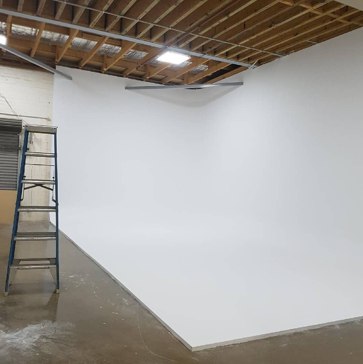Cyclorama wall installation in progress — exposed ceiling studio space