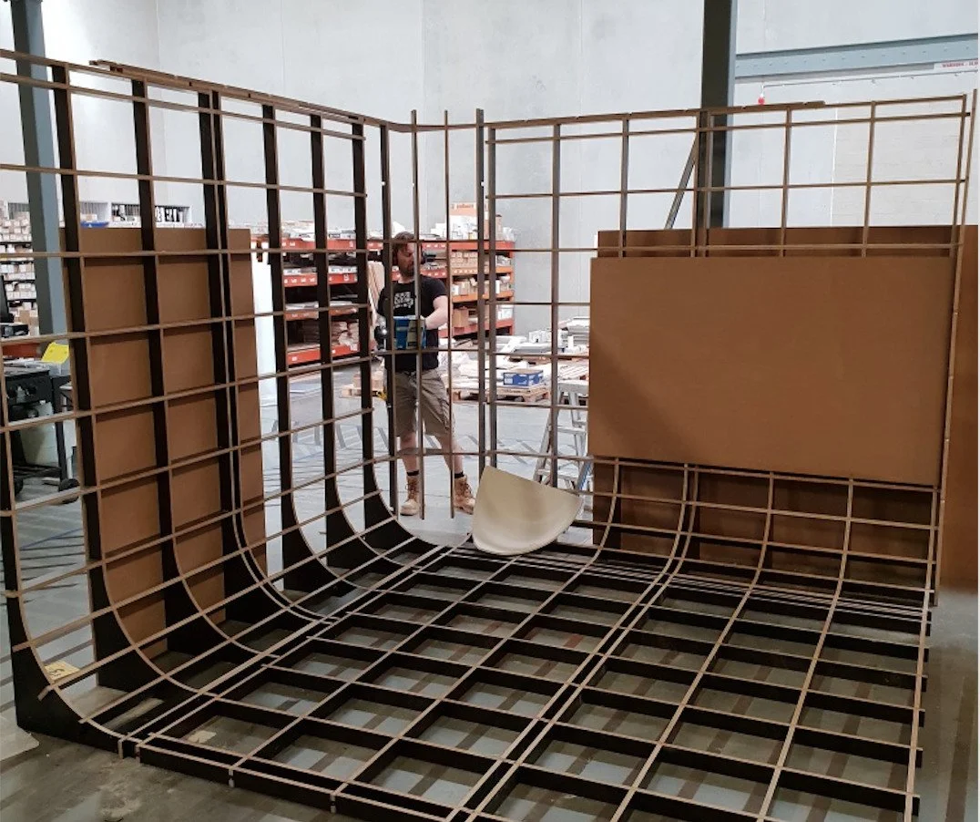 Covingsmith founder setting up curved plywood cyclorama frame during installation