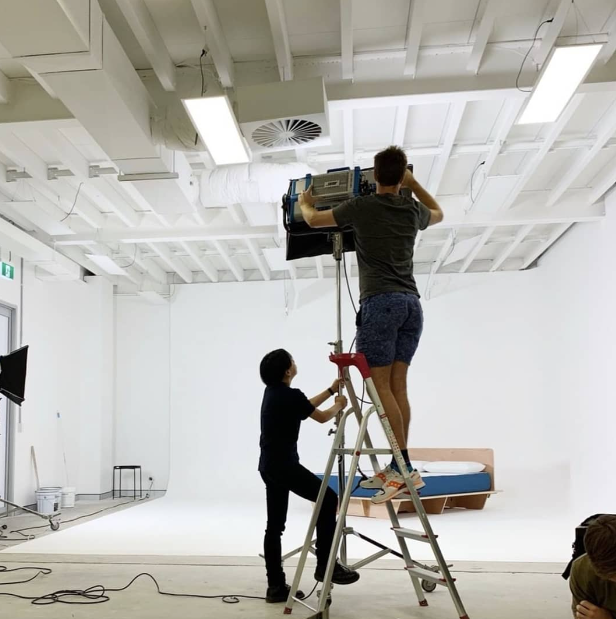 Crew setting up camera and lighting rig in white cyclorama studio