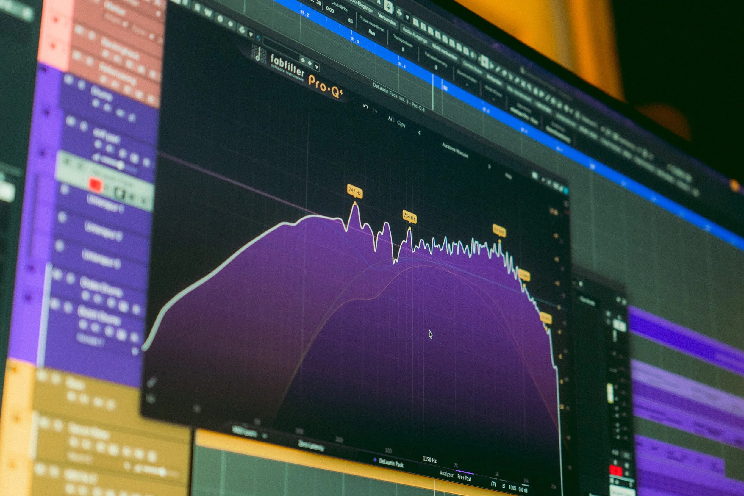 Ein Computerbildschirm, auf dem eine Audiobearbeitungssoftware mit Wellenformen, Equalizer-Einstellungen und mehreren bunten Spuren zu sehen ist.
