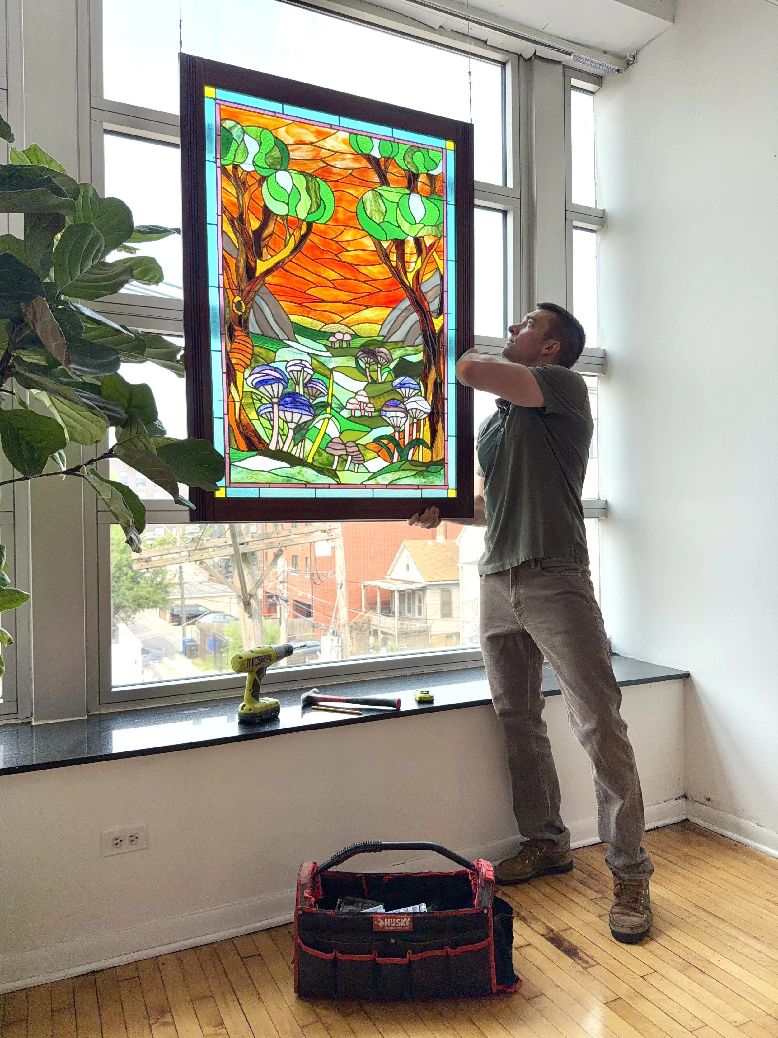 A man installing a colorful stained-glass window.