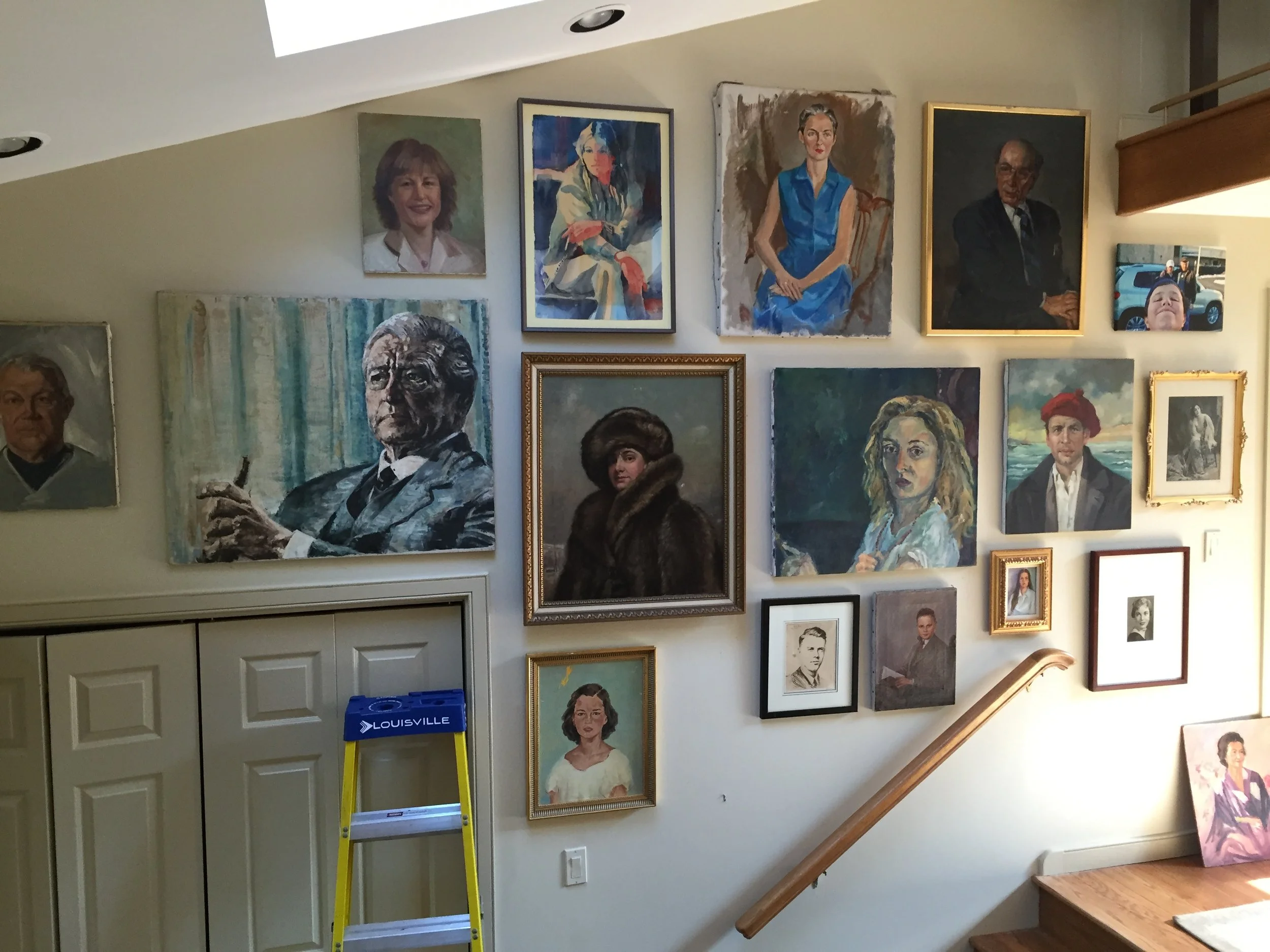 Gallery wall with various framed paintings and portraits, including a woman in a blue dress, a man in a suit, and other colorful artworks, with a ladder labeled 'Louisville' and a staircase railing nearby.