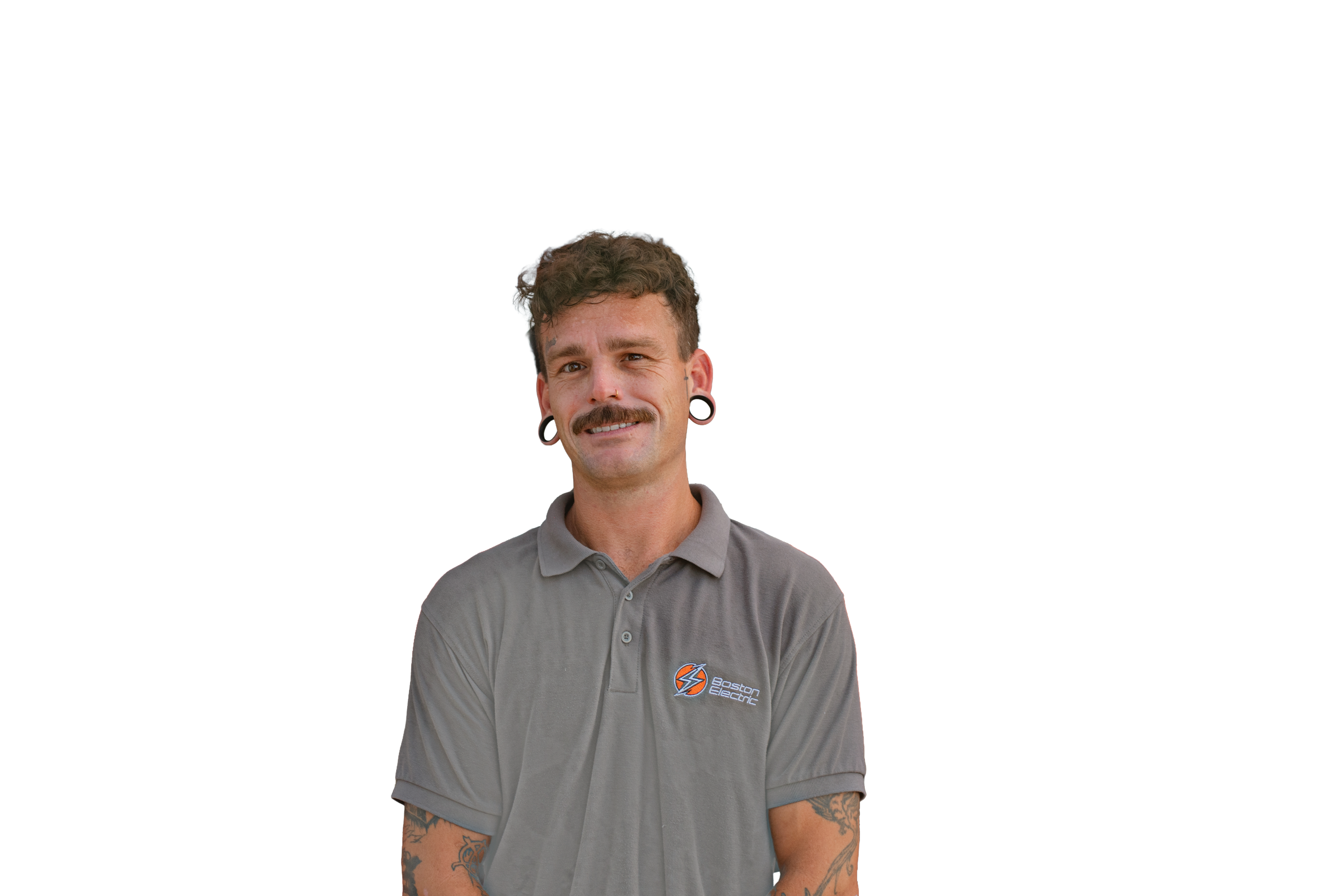 A young man with curly hair, a mustache, and tattoos on his arms, wearing a gray polo shirt with a Boston Electric logo, smiling at the camera.