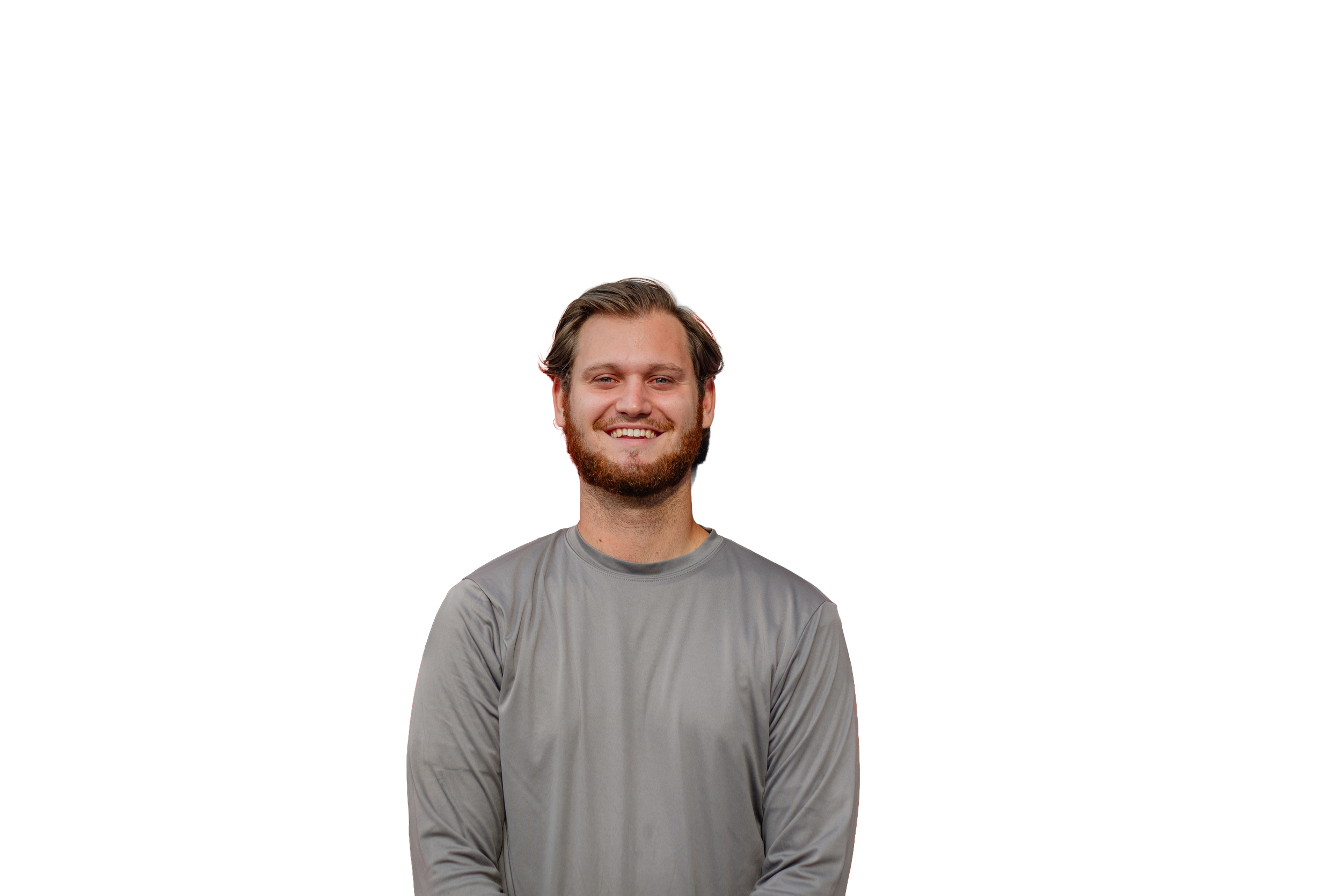 A smiling young man with a beard and long hair, wearing a gray long-sleeve shirt, stands against a black background with colored lines.