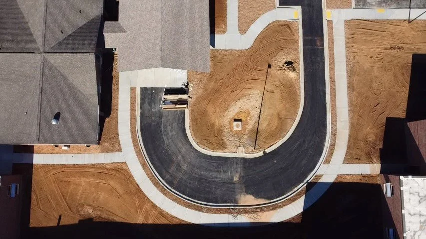 Aerial view of a cul-de-sac in a residential neighborhood under construction, with new sidewalks and bare ground surrounding the street.