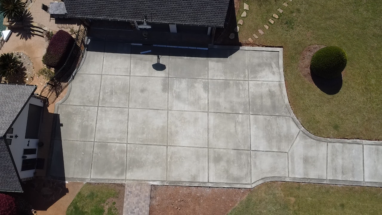 Aerial view of a residential backyard with a concrete patio, small landscaped garden, and lawn area.