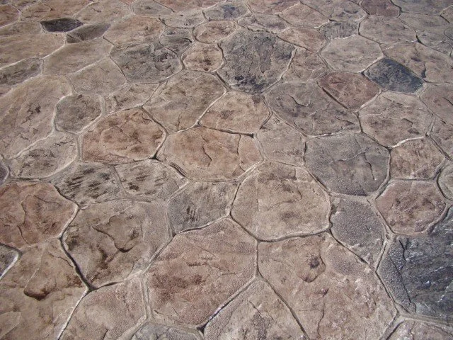 Close-up of a stone floor with irregularly shaped stones in shades of brown and gray, separated by grout lines.