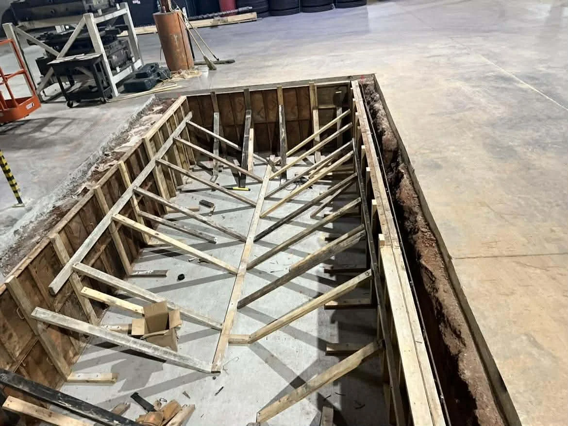 Wooden framing inside a construction site, with construction tools around, in an empty warehouse.