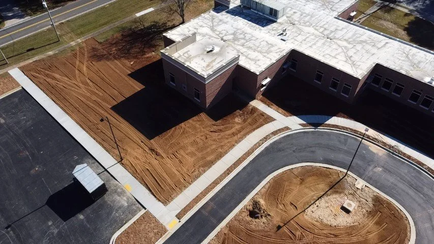 Aerial view of a building under construction with surrounding dirt and freshly paved roads.