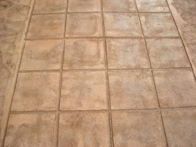 A tiled floor with beige square tiles and grout lines.