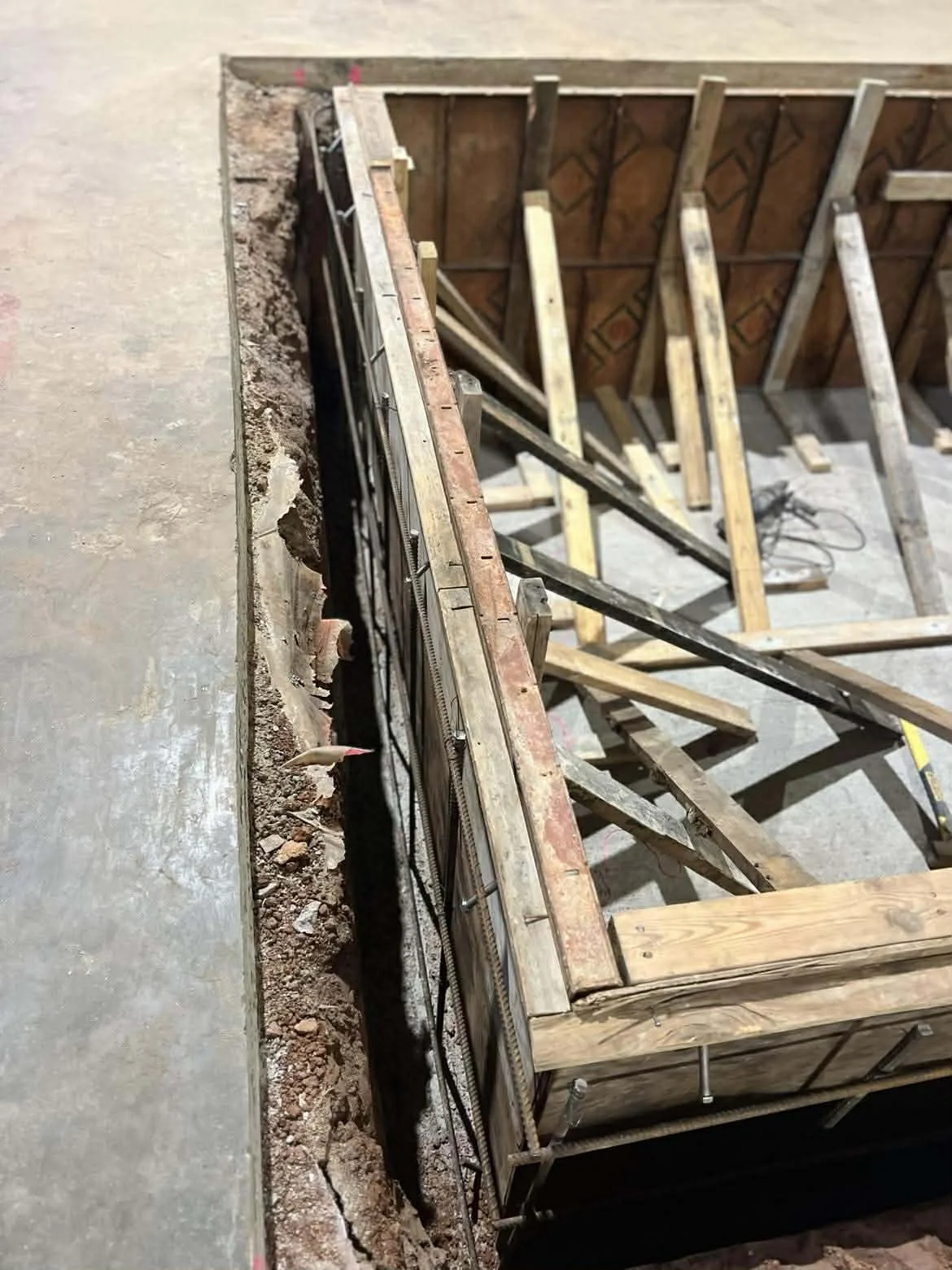 Construction site with wooden framing and metal reinforcement for a wall or floor.