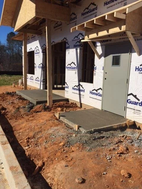 Construction site showing the entrance to a building under construction with concrete steps and wood framing, wrapped in HomeGuard building wrap.