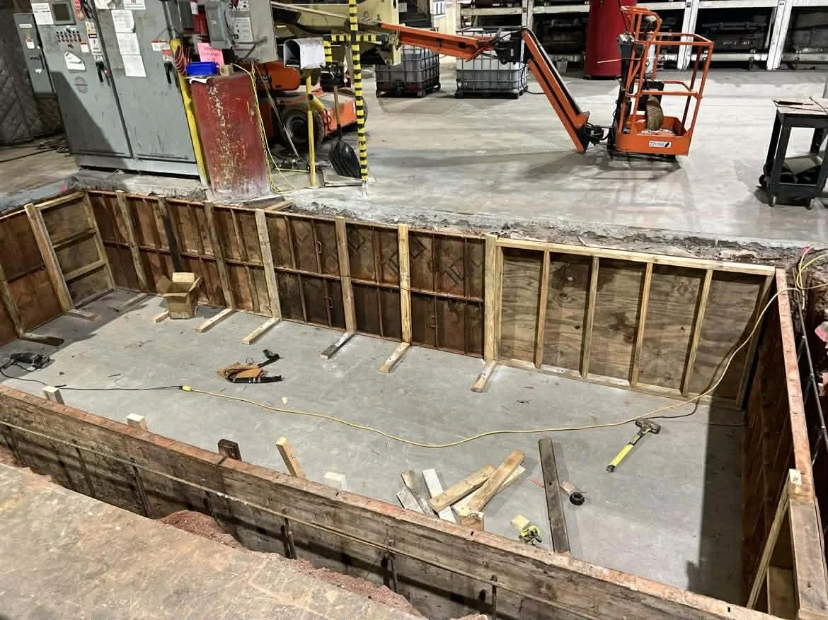 Construction site with a wooden frame structure and concrete floor, construction tools, and equipment.