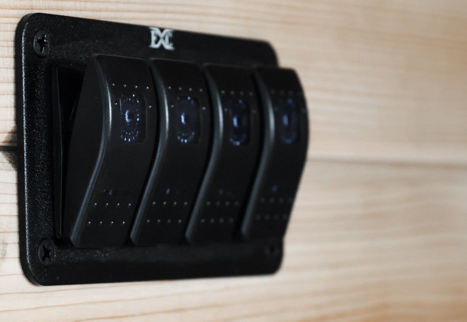 Black light switch attached to the wooden wall of a sauna.