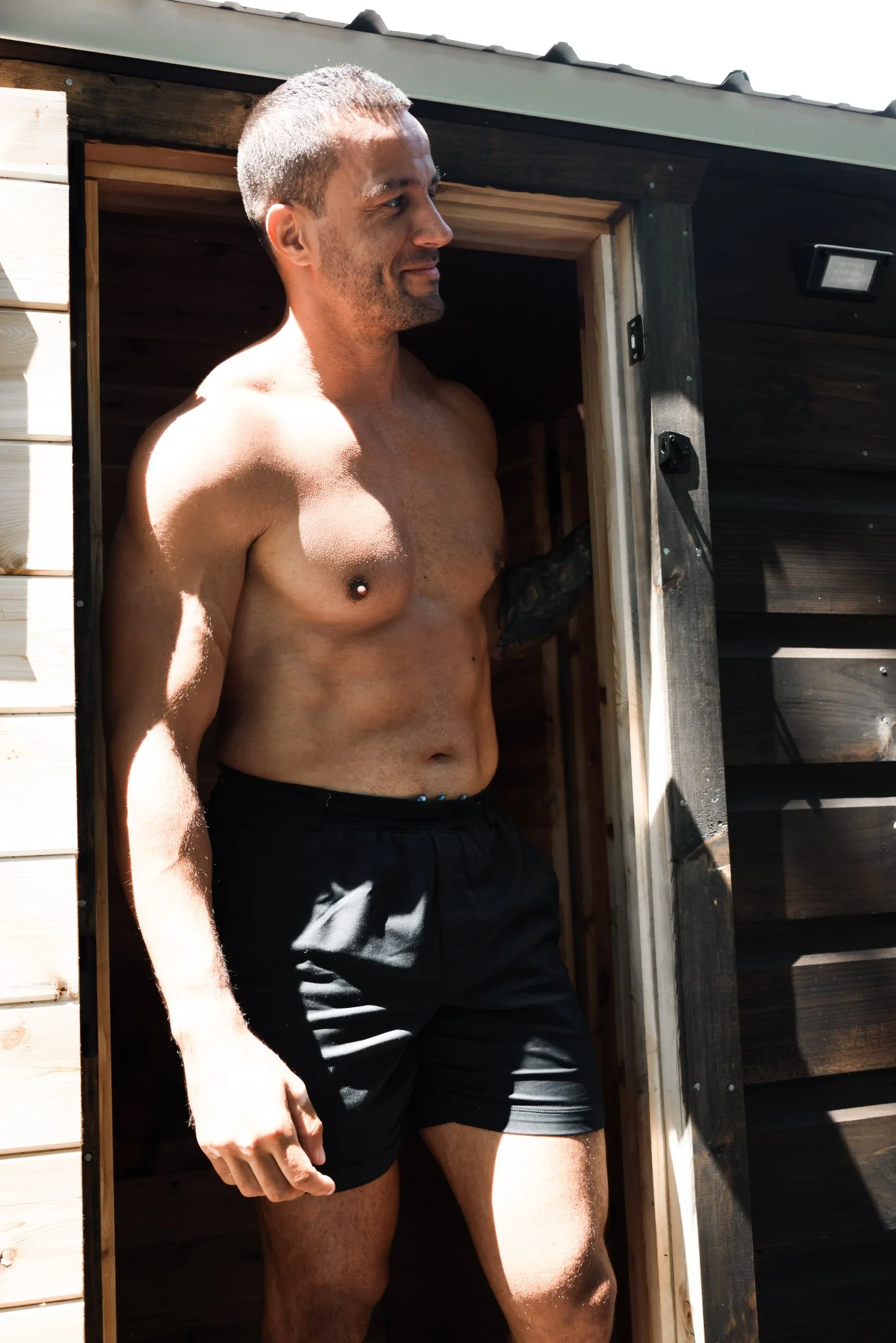 Man stepping outside of a traditional wood-fired mobile sauna.