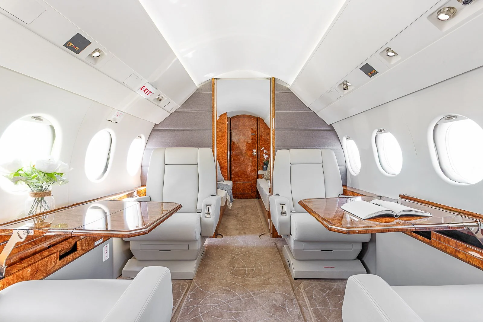 Private jet cabin interior with leather seats and wood finishes.
