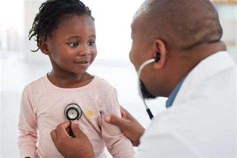 A young girl is seeing a doctor, who is using a stethoscope to listen to her chest.