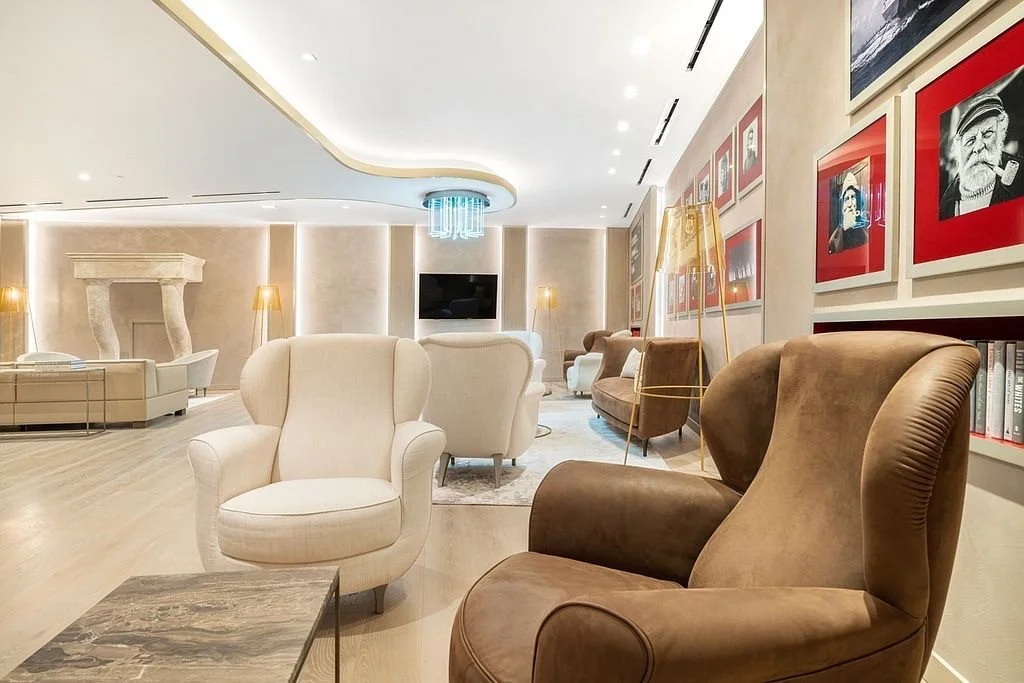 Elegant hotel lobby with beige and brown chairs, a small coffee table, and framed photos on the wall.