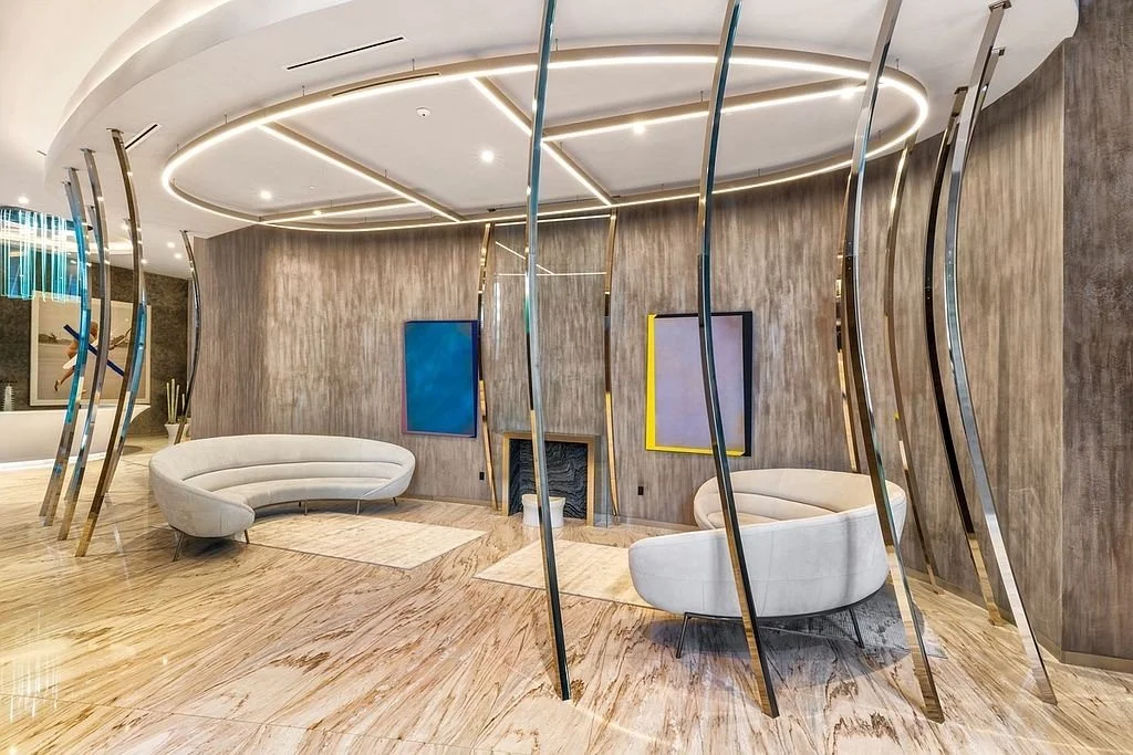Modern interior space with curved white sofas, unique curved metal and glass dividers, wood floors, and contemporary wall art.