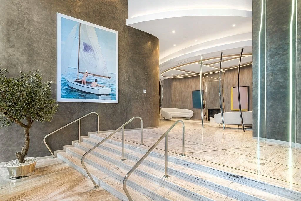 Modern hotel lobby with marble floors, abstract art, and curved design elements.