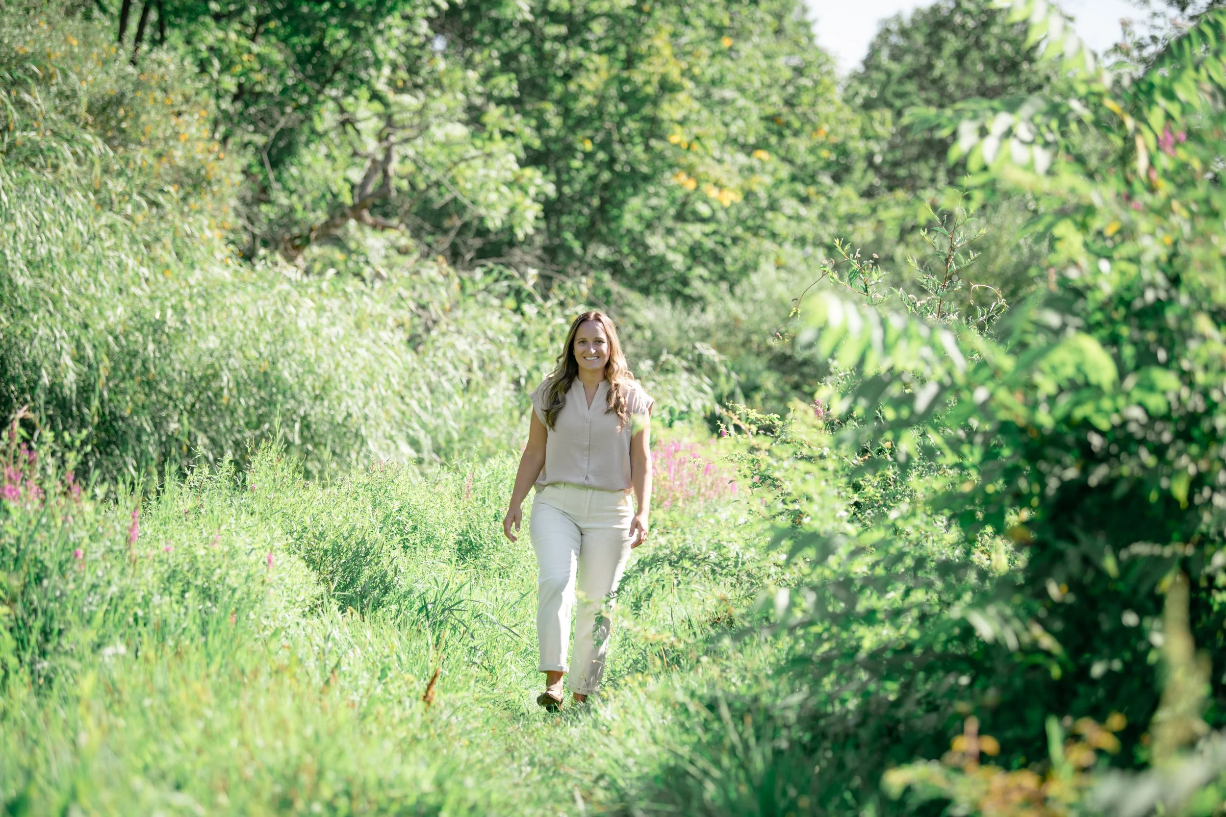 Melissa Parrish, LPC, walking through greenery toward the camera, smiling