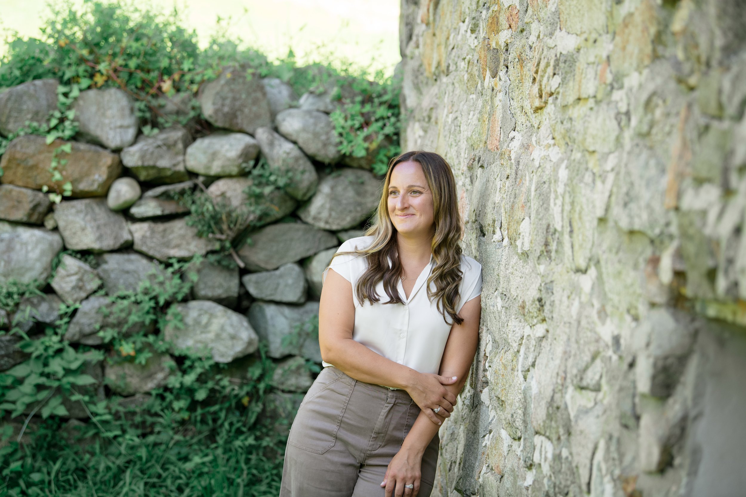 Melissa Parrish, LPC, leaning against a stone wall and smiling off camera