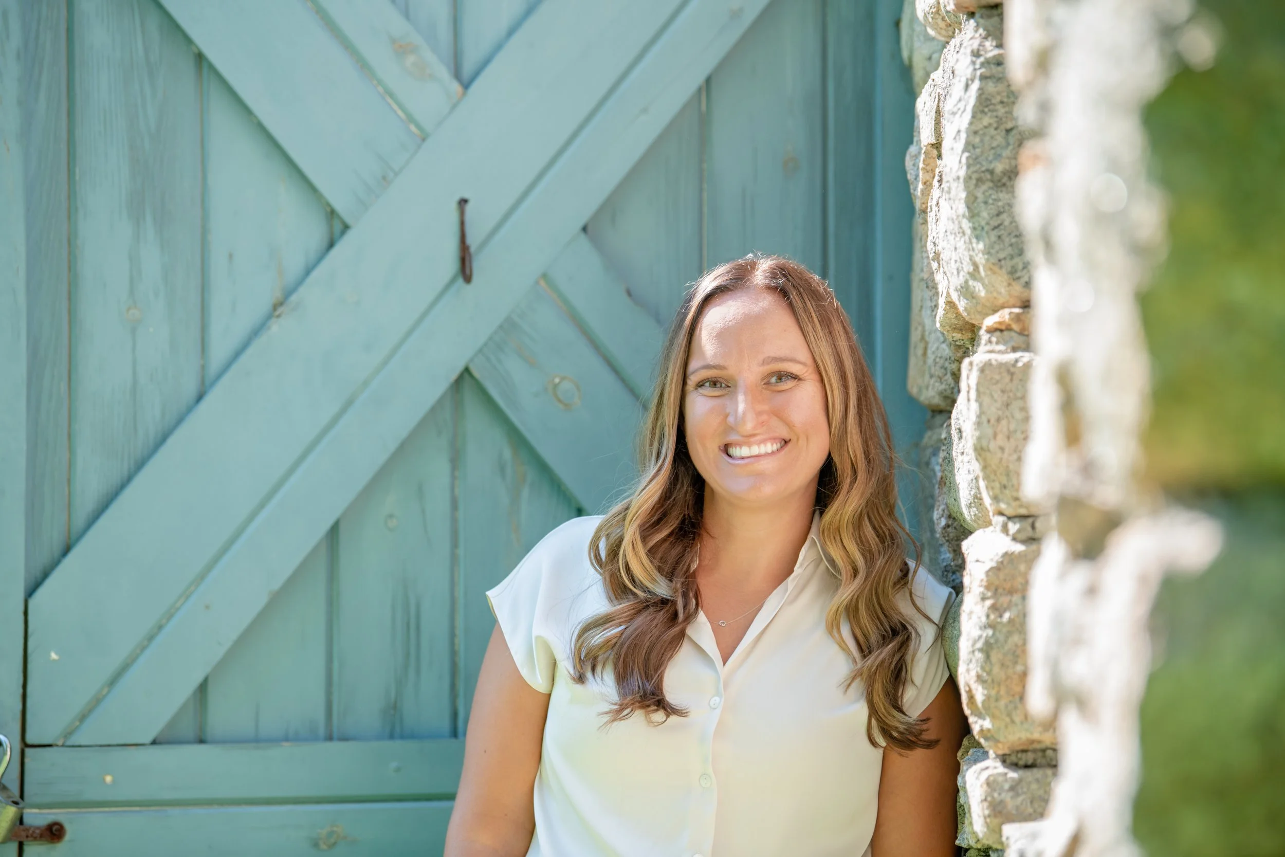 Melissa Parrish, LPC, standing in front of a teal door, smiling at the camera