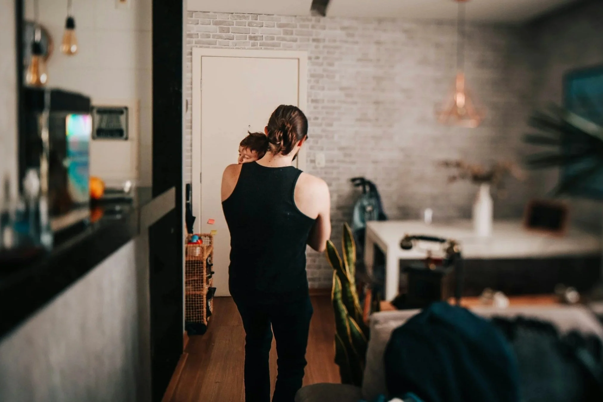 Adult carrying a sleeping child through the house, seen from behind