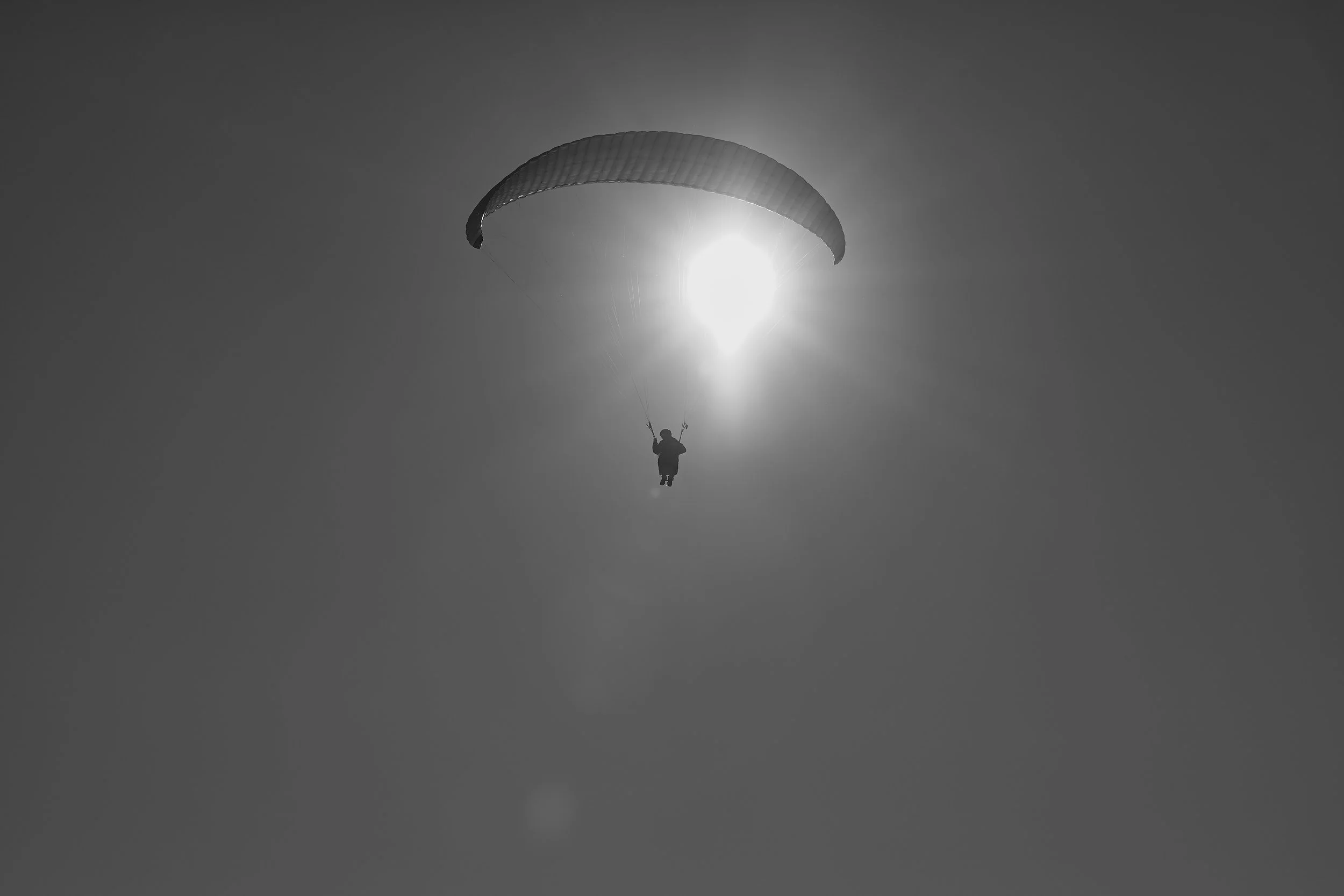 En person, der flyver med paraglider mod en solrig himmel.