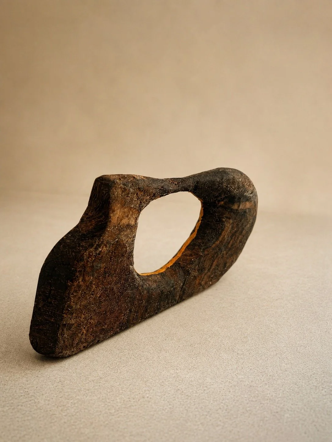 Dark hand-carved wood sculpture with an irregular central opening
