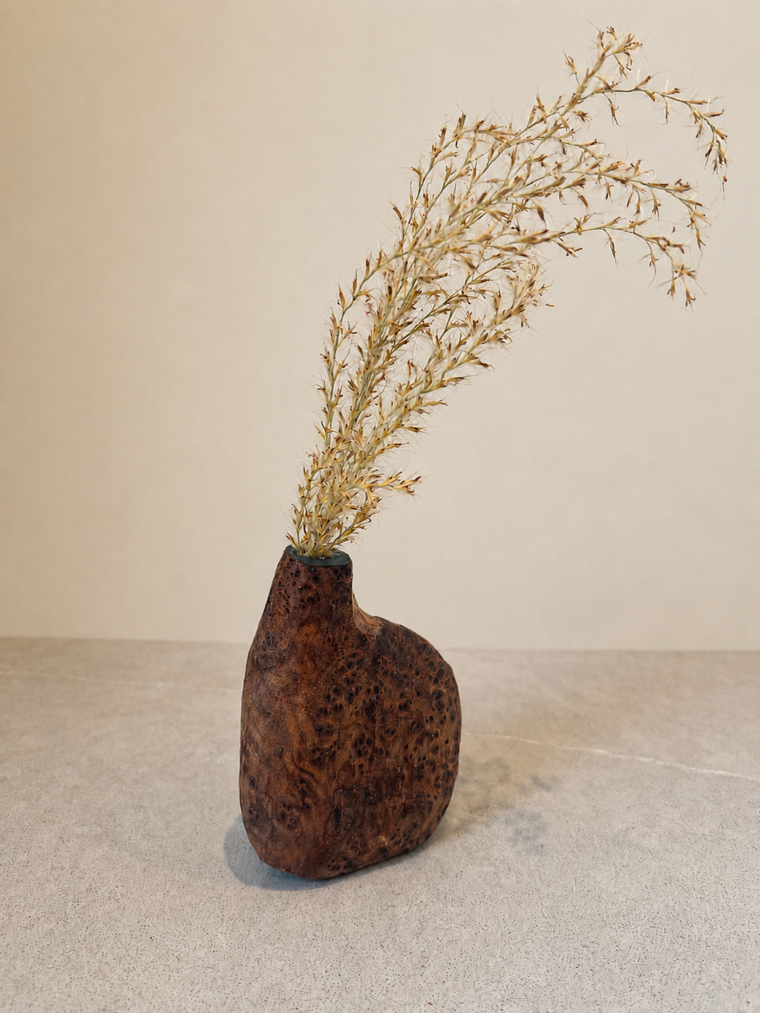 Hand-carved redwood vessel holding dried grasses