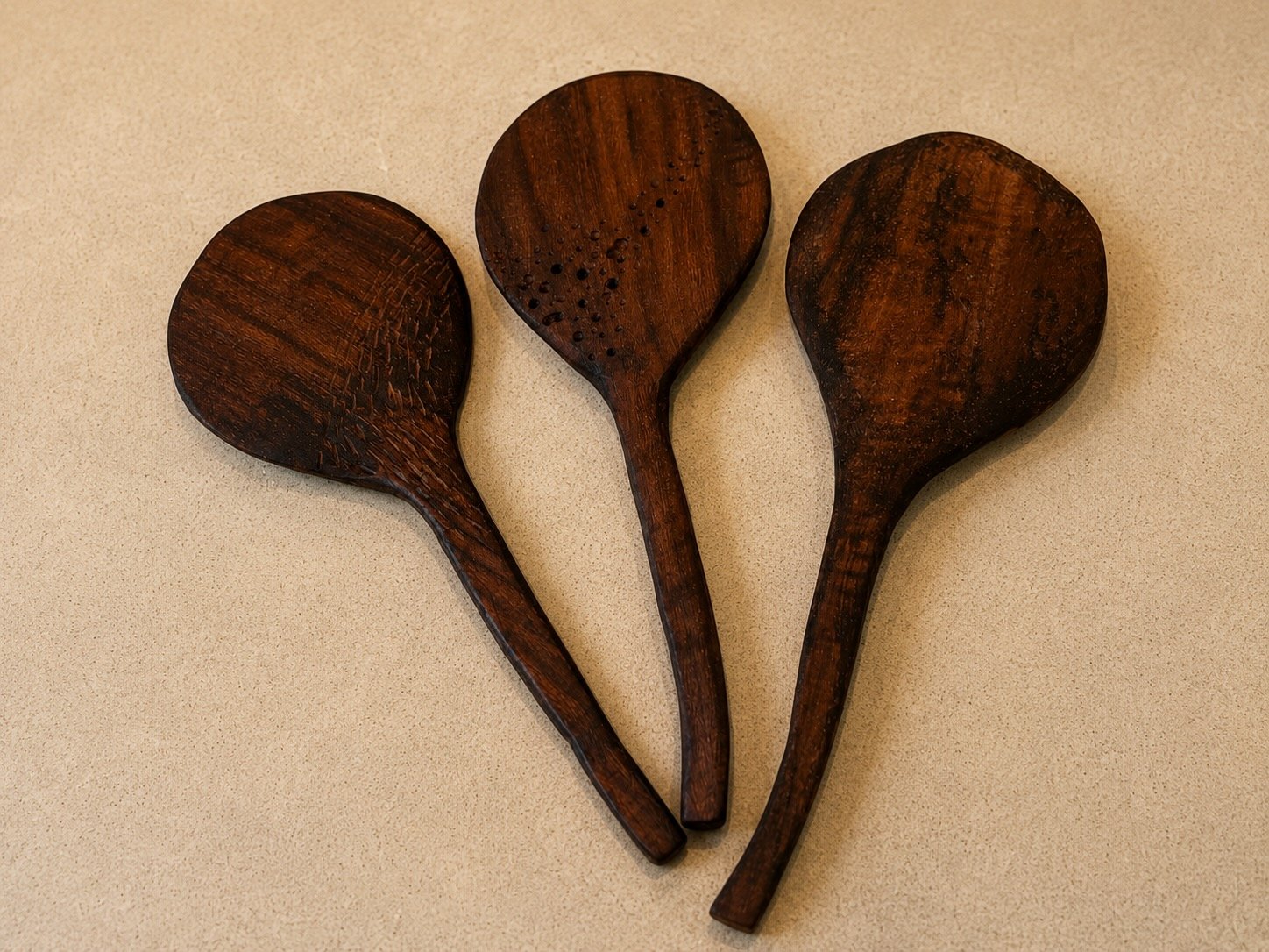 Three hand-carved dark rice paddles