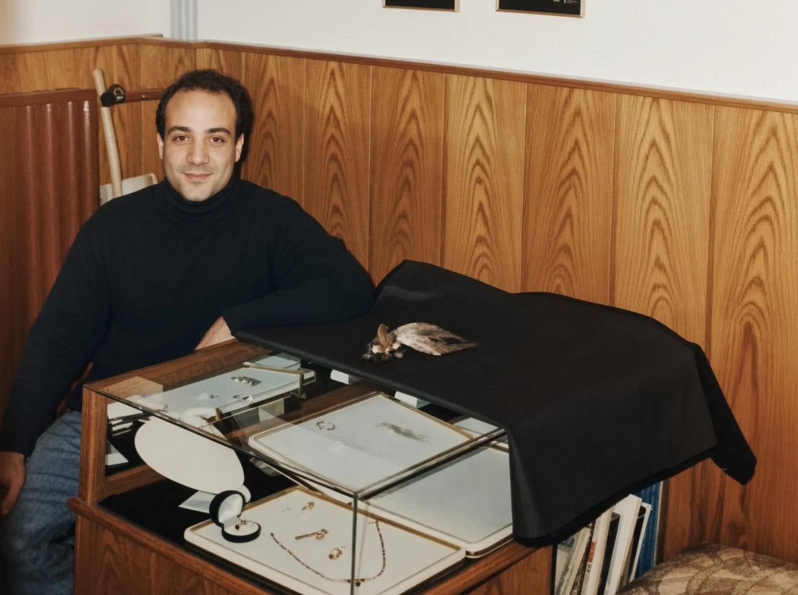 Jeweler seated beside glass jewelry display cases in his Istanbul shop.