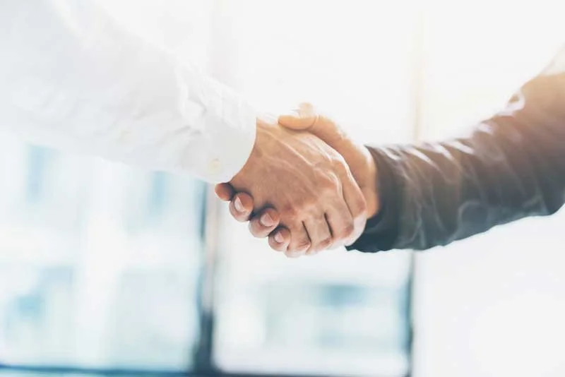 Two people shaking hands in a business setting.