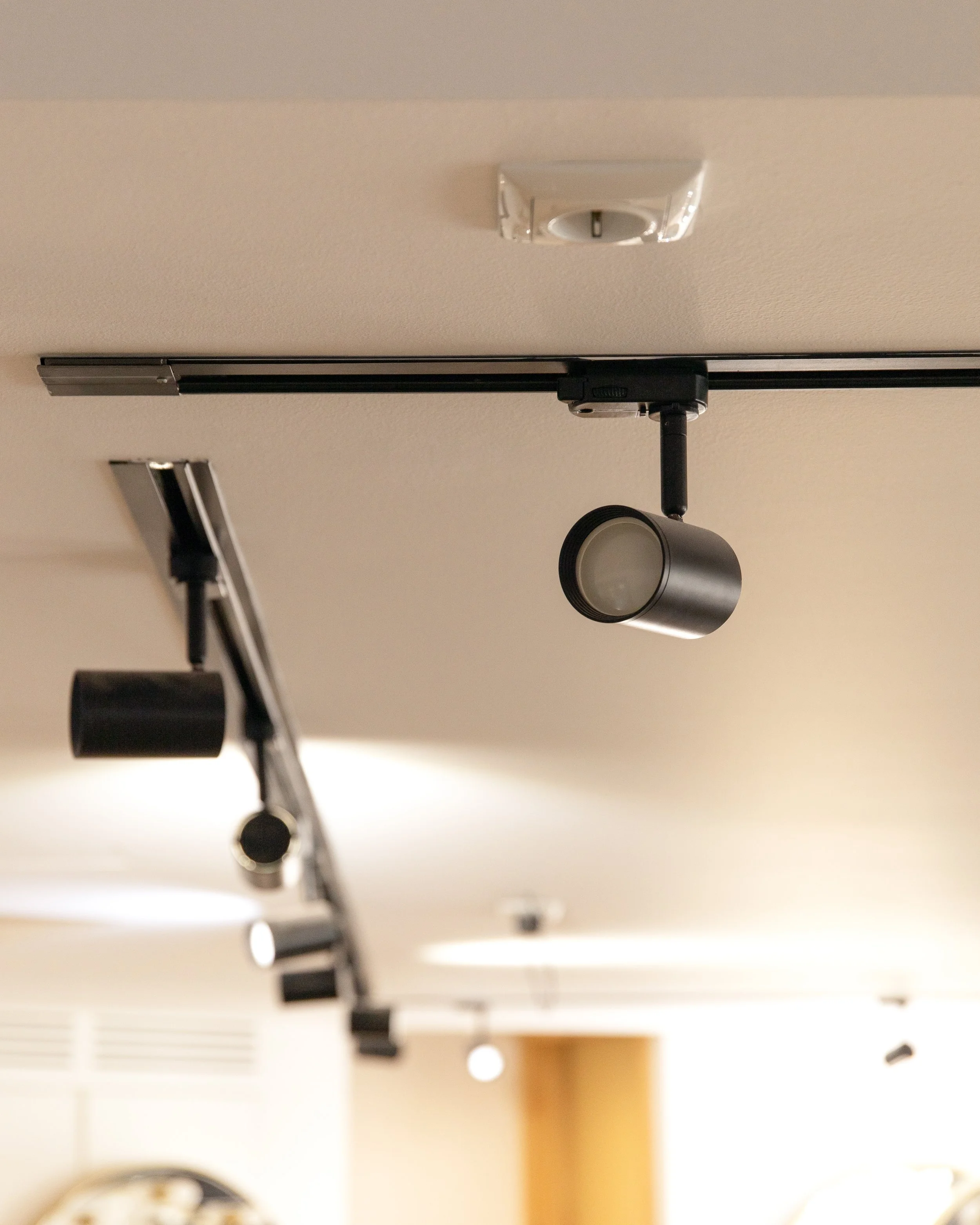 Ceiling-mounted track lighting fixtures with adjustable spotlights, viewed from below.