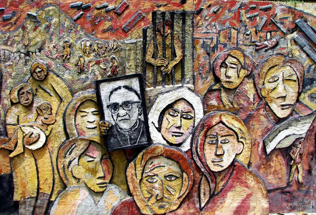 A textured mural depicting a protest scene with multiple faces of diverse women and men, some with halos, and a person holding a framed portrait of a man with glasses. The background shows hands and other figures.