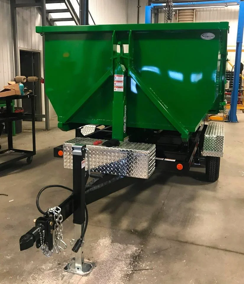 Green industrial trailer with metal diamond plate toolbox at the front, parked inside a warehouse or workshop.