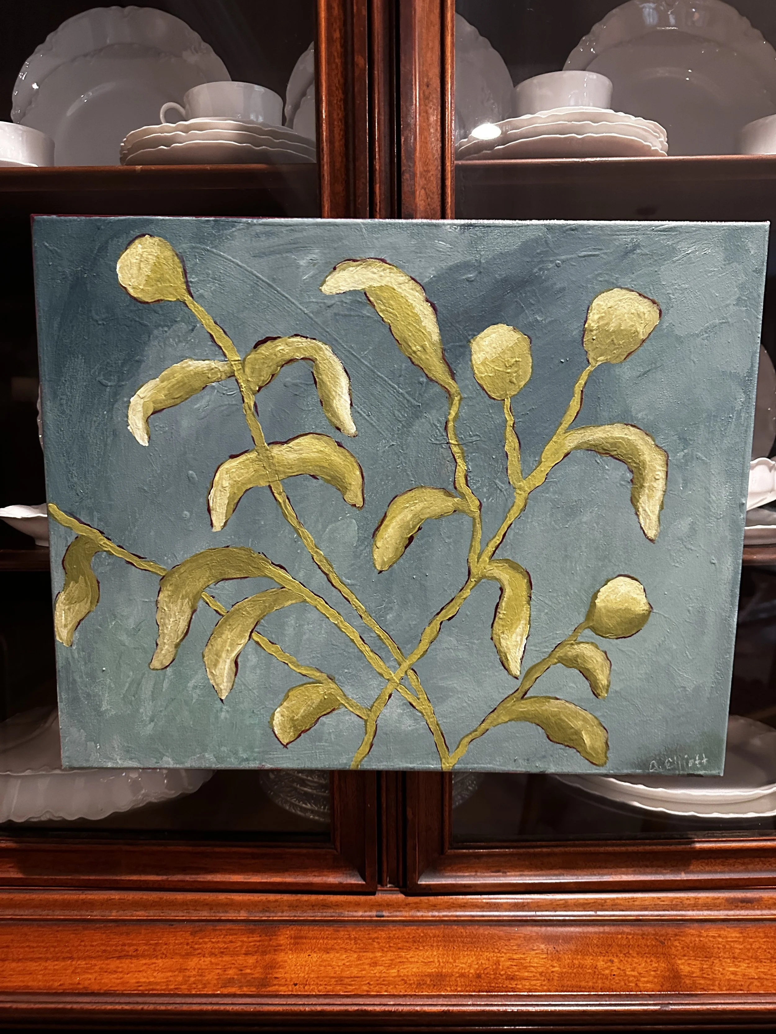 A decorative hand-painted artwork of a plant with yellow leaves against a blue background, signed in the bottom right corner.