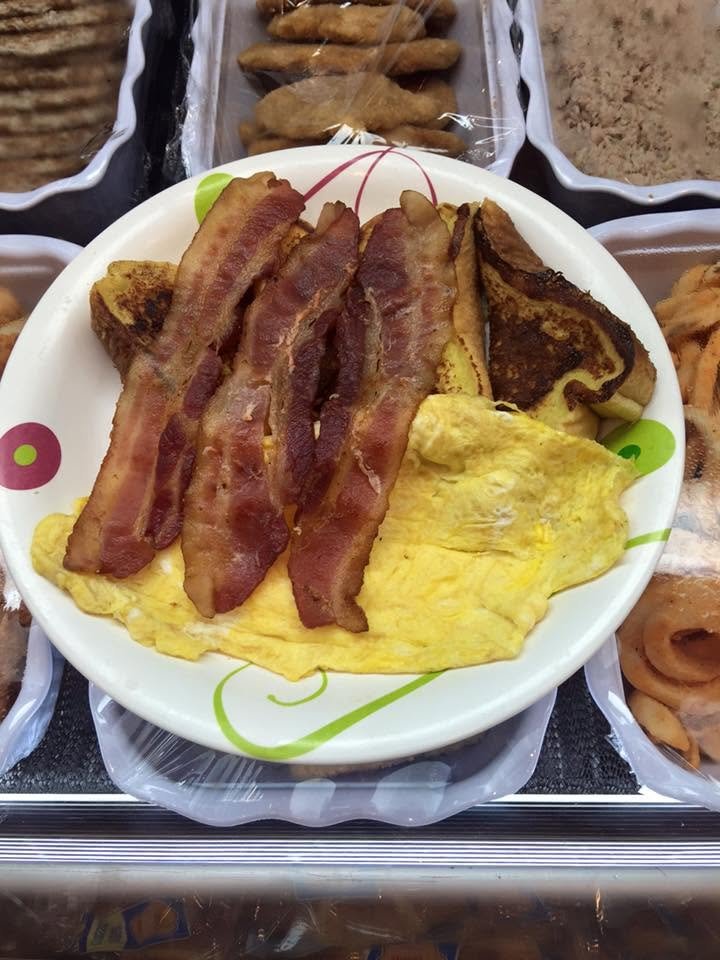 Bacon, scrambled eggs, and a burnt pancake on a white plate with green and pink circle patterns.