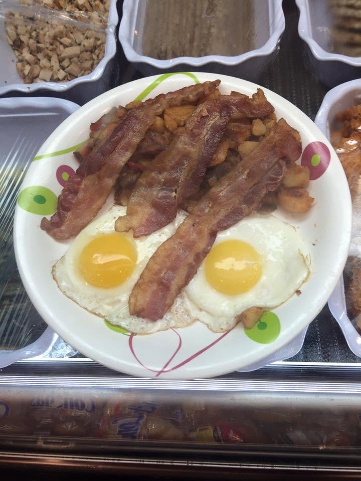 A plate with two fried eggs and several strips of cooked bacon.