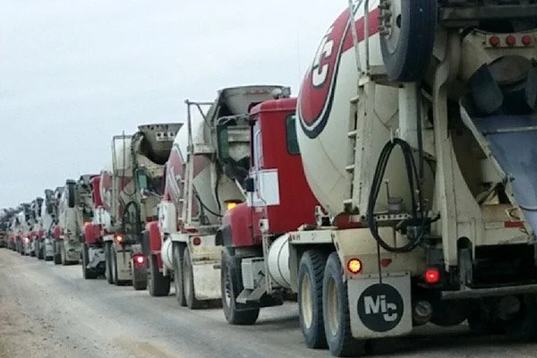Line of cement mixer trucks on a dirt road
