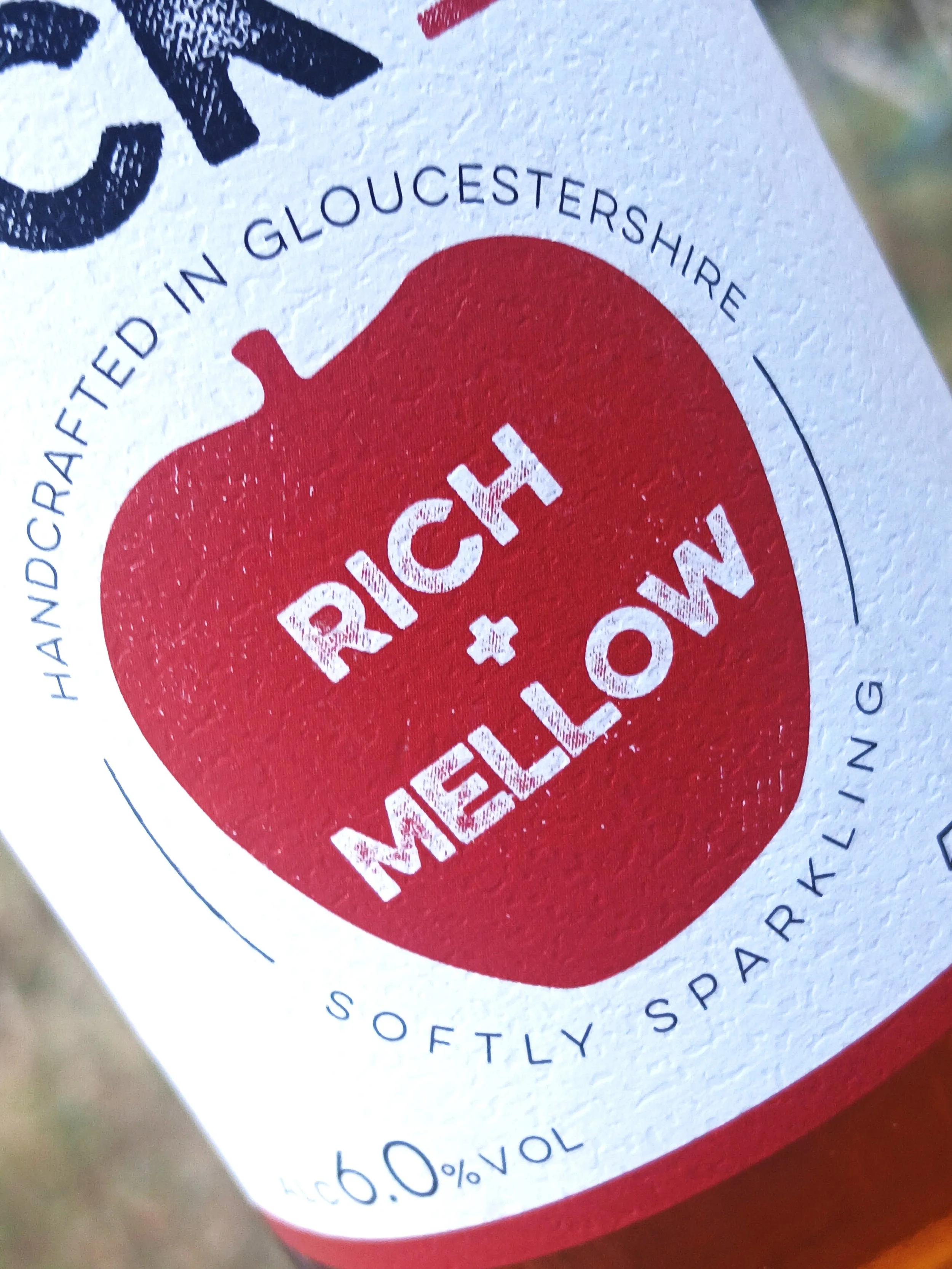 Close-up of a label showing 'Cream Cheese' with the original packaging design, including a red circle background and text indicating it is made in Gloucestershire, with nutritional information about 10.4% fat.